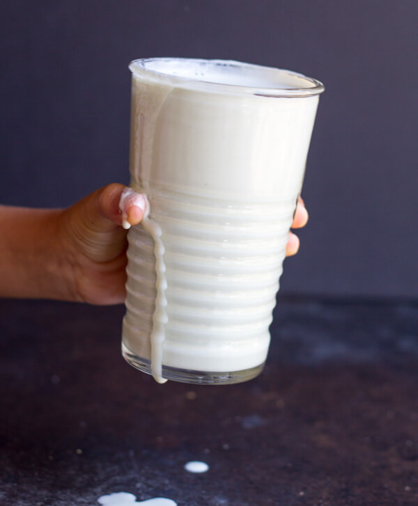hand holding a glass of dripping milk