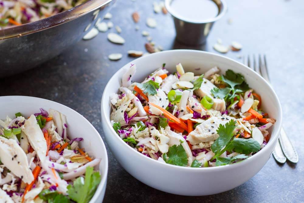 Chinese Chicken Salad on dark table with a side of dressing