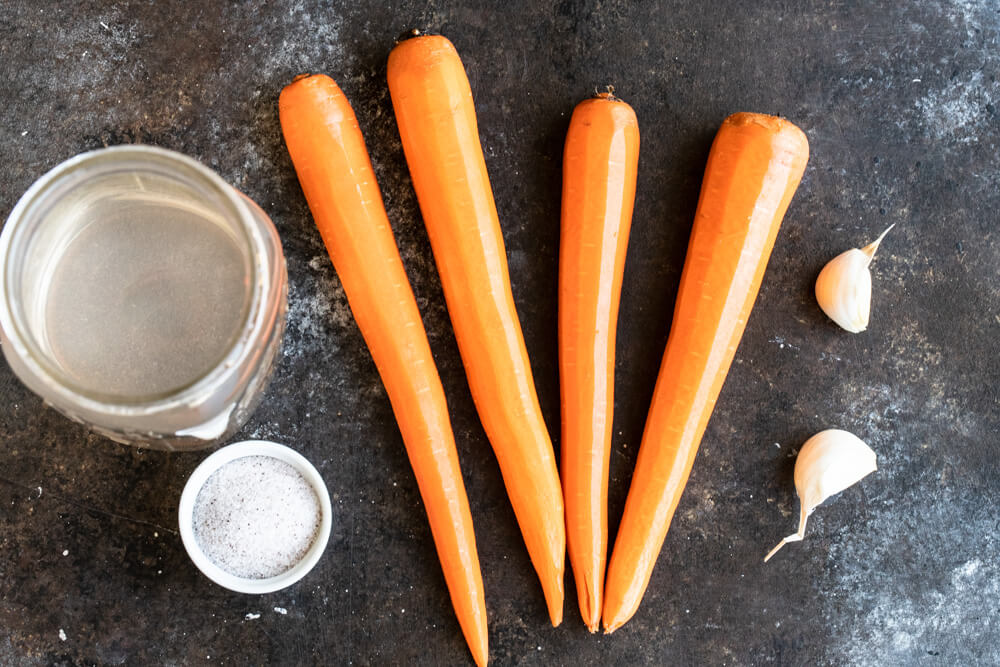 four carrots and two cloves of garlic on table