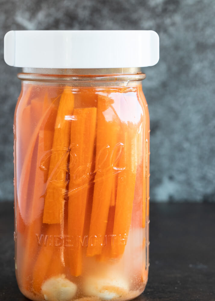 close up of fermentation lid on top of mason jar with carrots inside