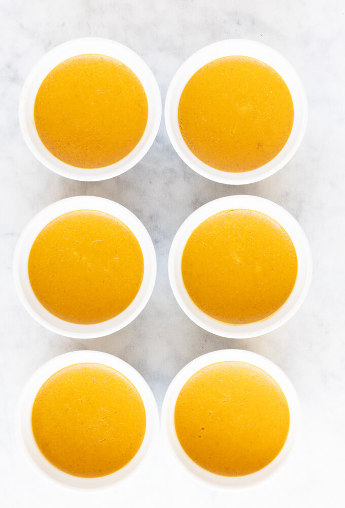six white ramekins of pumpkin custard