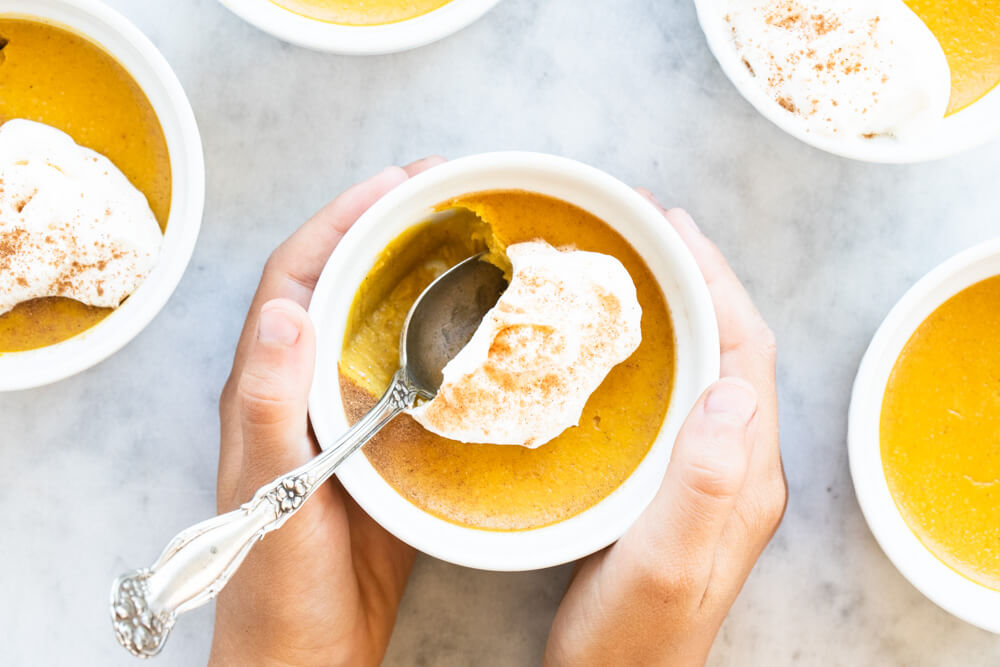 hands holding white bowl of custard