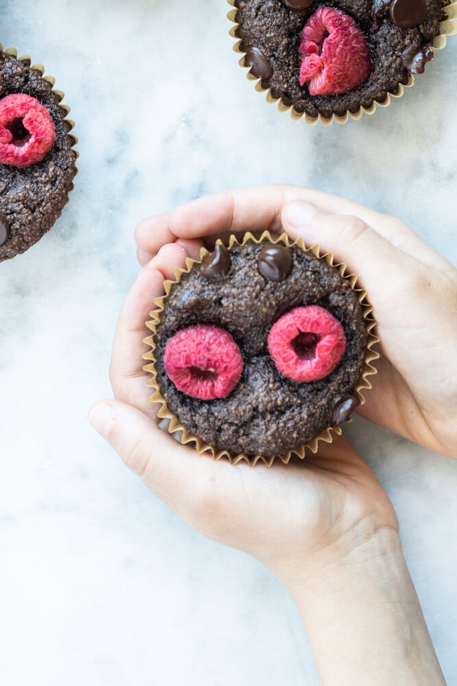 child's hand holding a vegan chocolate muffin