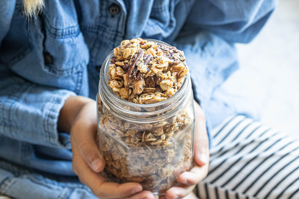 hands holding glass jar of granola