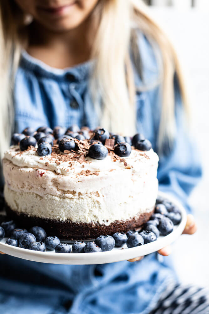 child holding white plate with ice cream cake