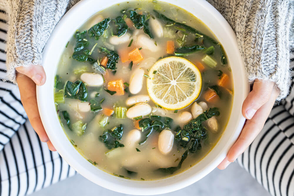white bowl of soup sitting in person's lap