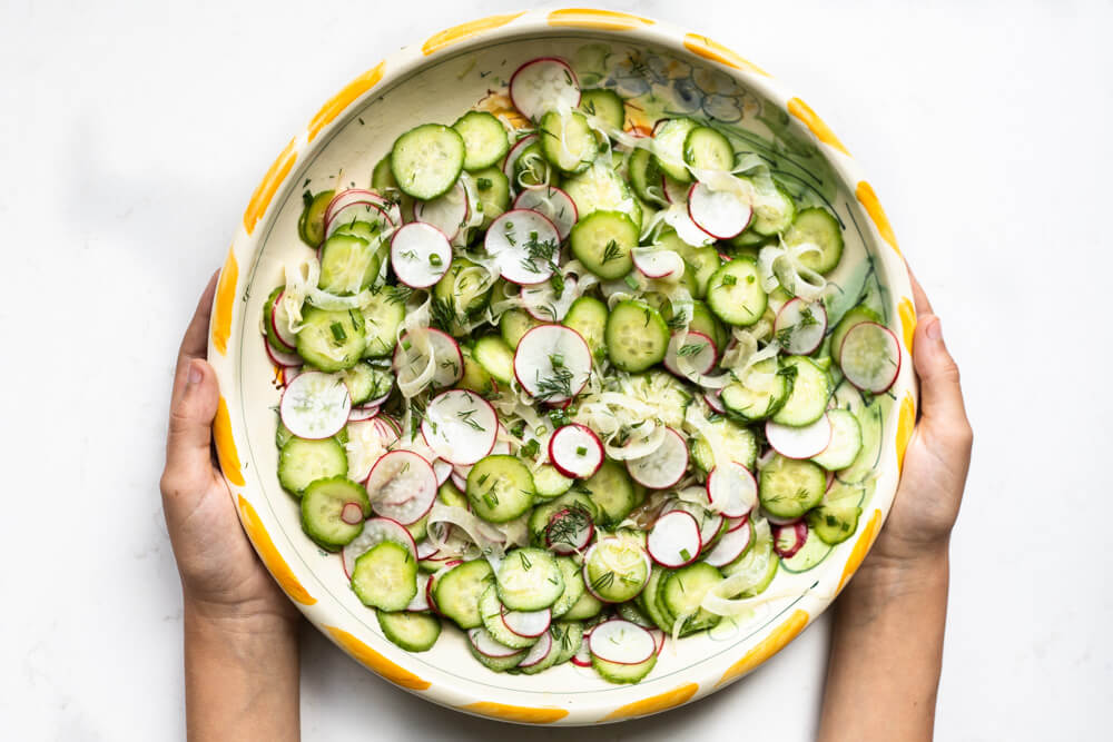 hands holding cucumber salad