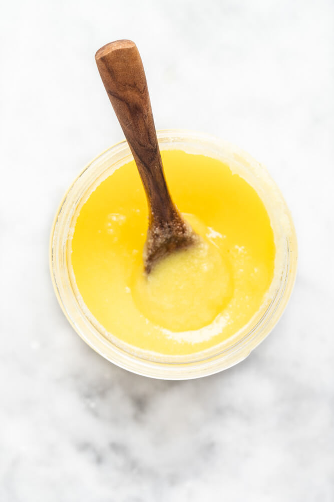 glass jar of ghee with wooden spoon in it