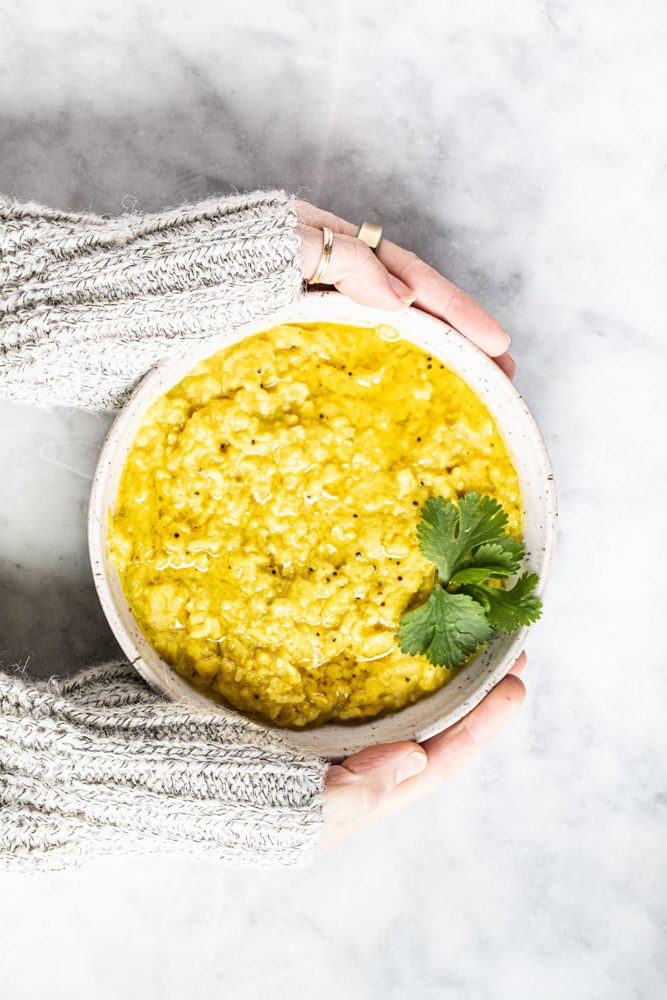 hands holding bowl of kitchari
