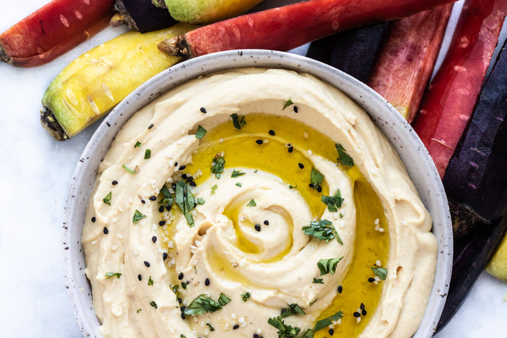 hummus in white bowl with carrots